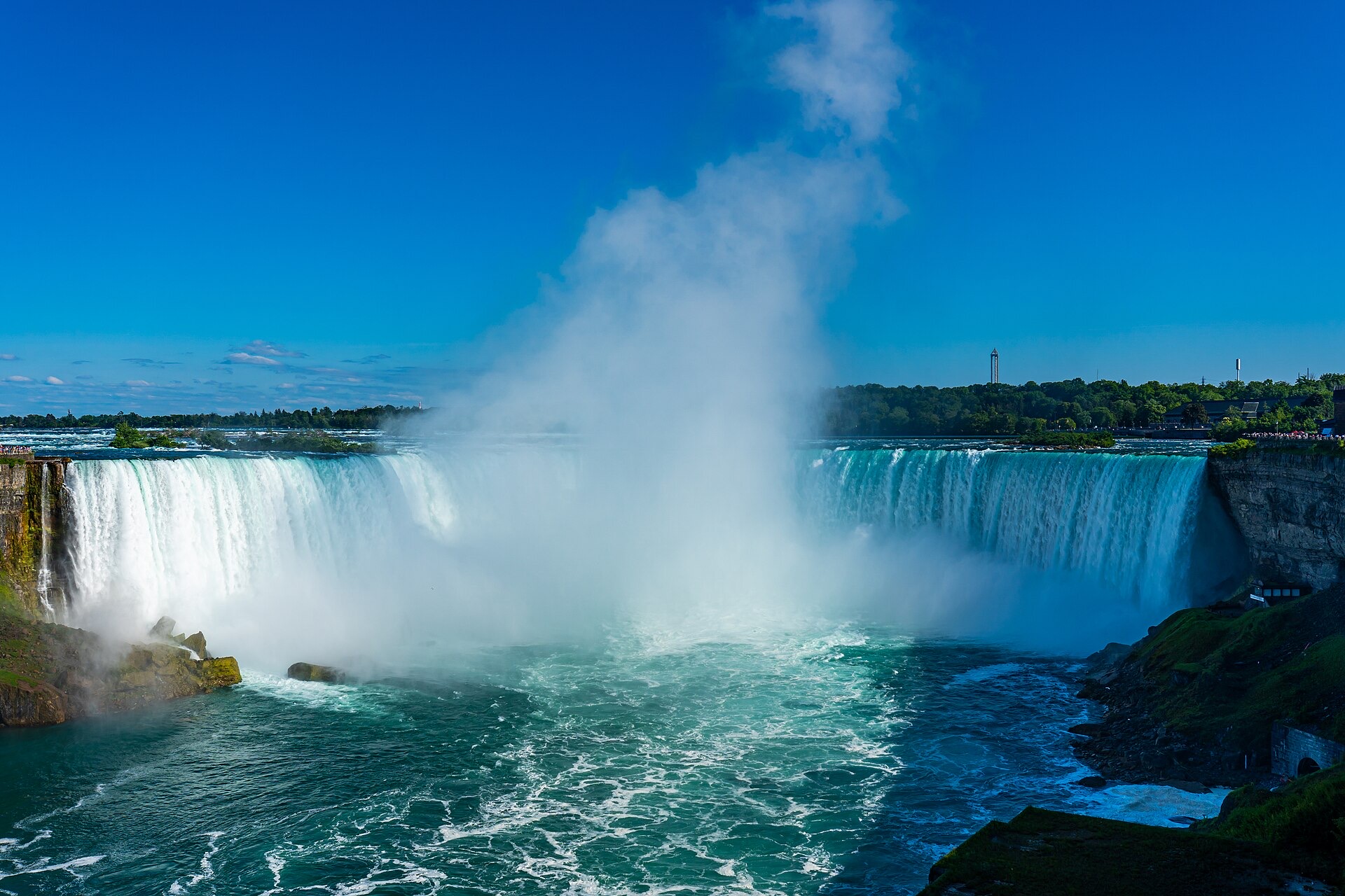 The Horseshoe Falls at Niagara Falls, Ontario, with spray rising under a clear blue sky