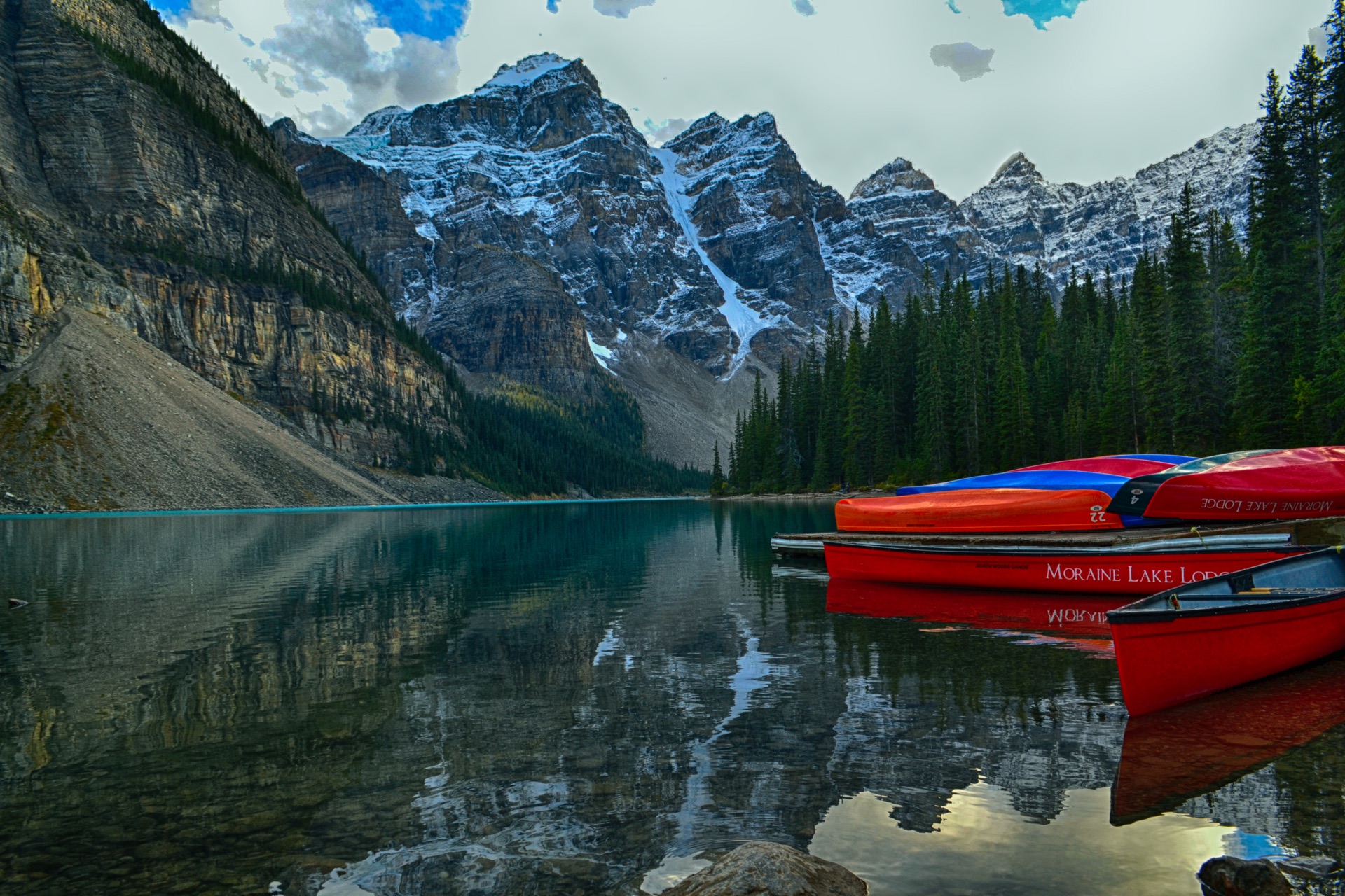 Red canoes on the turquoise water of Moraine Lake in Banff National Park with the Valley of the Ten Peaks behind